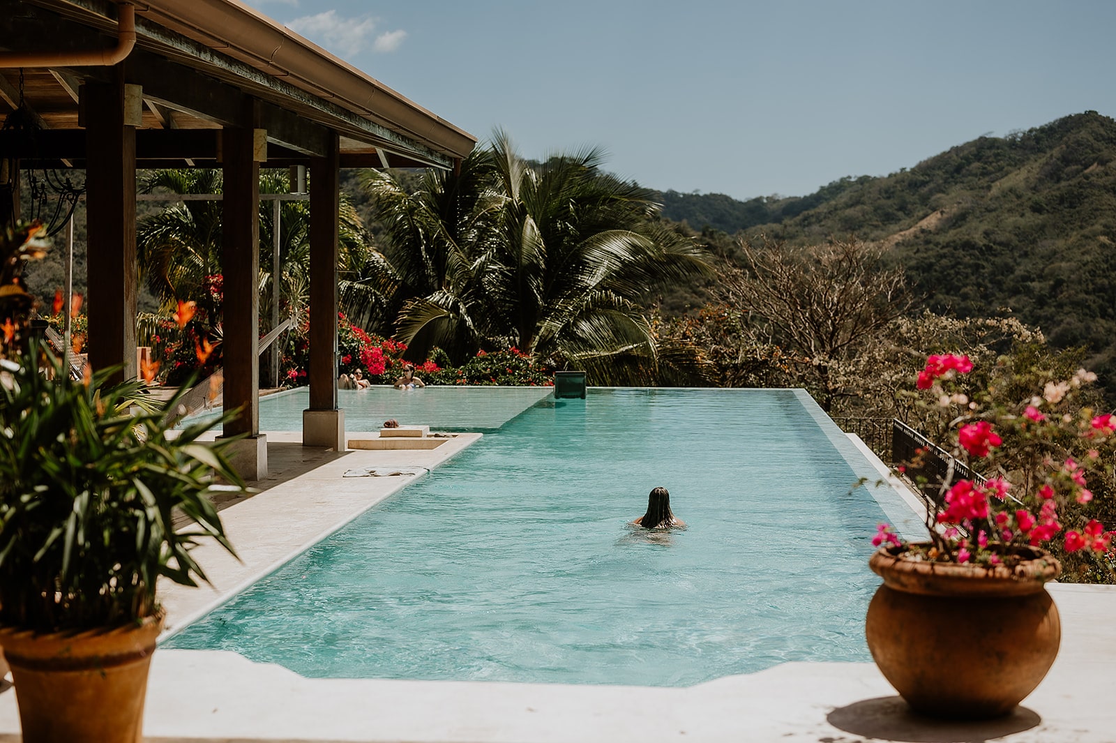 costa rica A woman is swimming in a pool in front of a mountain, captured beautifully by a Costa Rica photographer.