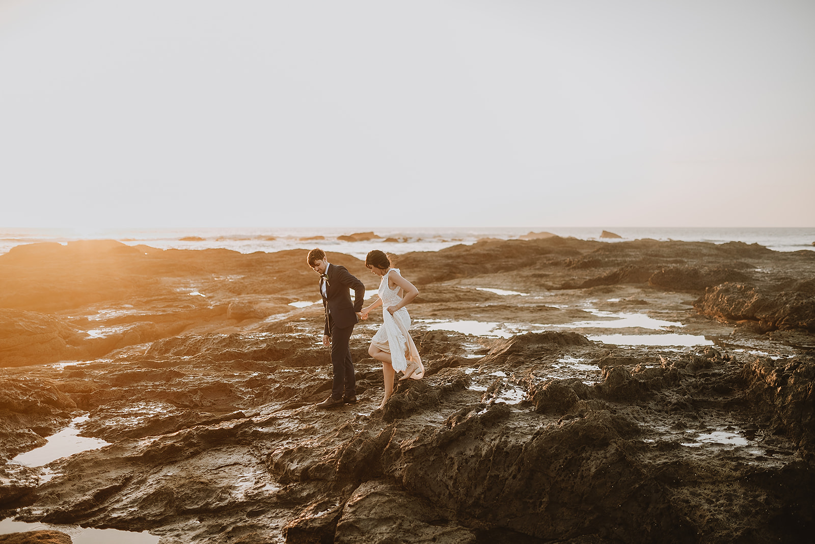 costa rica A wedding couple standing on playa rocks at sunset captured by a Costa Rica photographer.