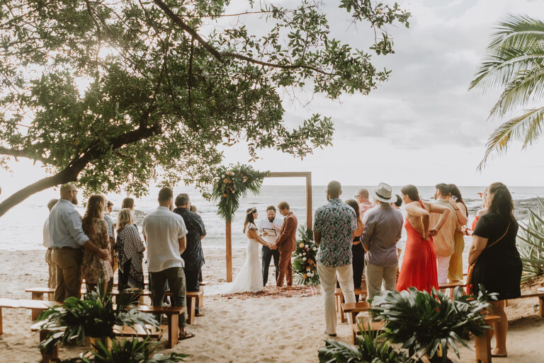 costa rica A playa wedding ceremony on the beach under palm trees, captured beautifully by a Costa Rica photographer.