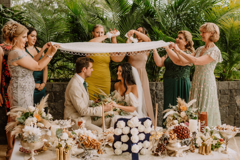 costa rica A wedding party is holding a wedding veil in front of a table for a beautiful beachside playa wedding photo