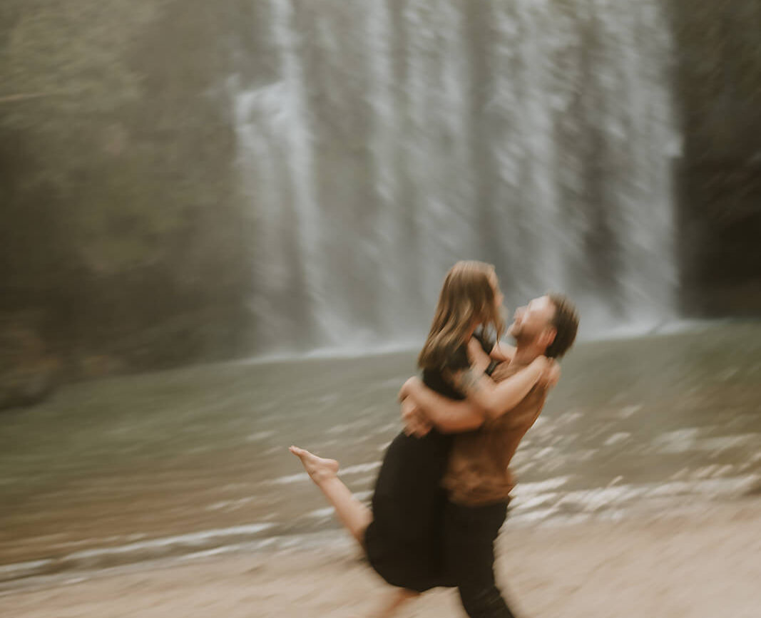 costa rica A man and woman sharing an intimate embrace in front of a breathtaking waterfall in Costa Rica, capturing their beautiful engagement photos.