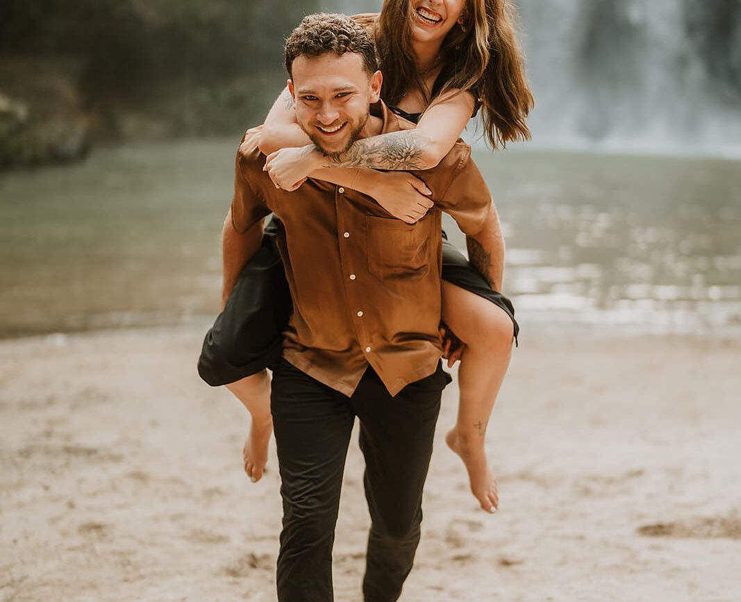 costa rica An engagement photographer captures breathtaking photos of a couple in Costa Rica, as a man lovingly carries his partner in front of a captivating waterfall.