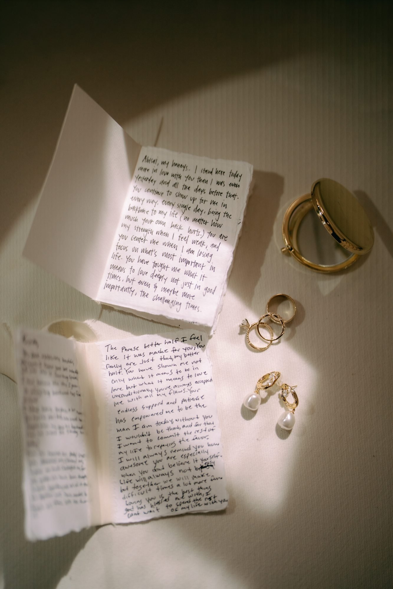 Handwritten wedding vows laid flat beside two rings and a pair of gold earrings, photographed by a Costa Rica elopement photographer