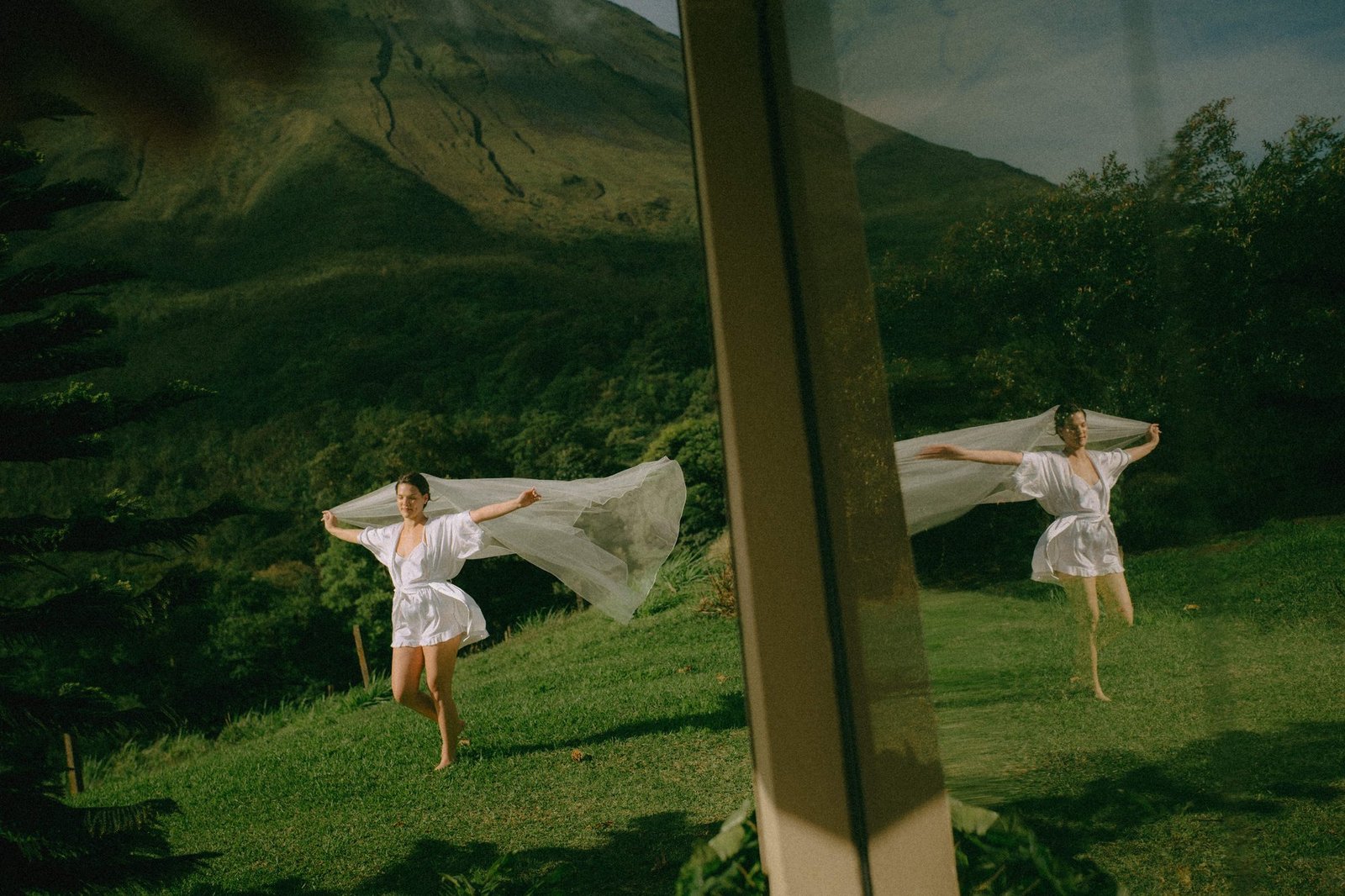 Two people in white turn and spin on a green hillside, their clothing blurred with movement
