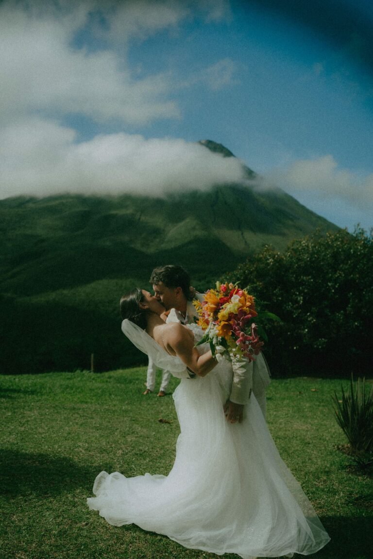 Best Documentary Wedding Photographers In Costa Rica | Adri and Lucas 21 Bride and groom embracing below Arenal Volcano with a tropical bouquet, Costa Rica