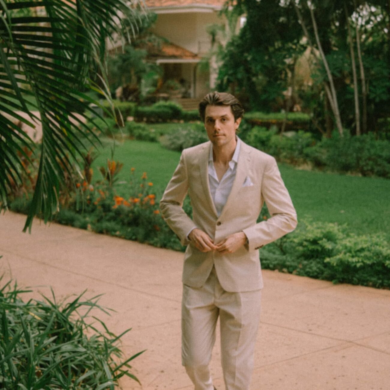 The groom walking along a garden path at Pangas Beach Club in Tamarindo