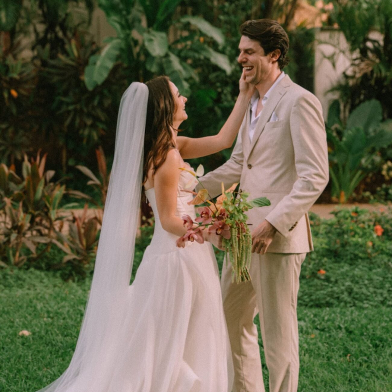 The bride touching the groom’s face as they laugh together before the ceremony