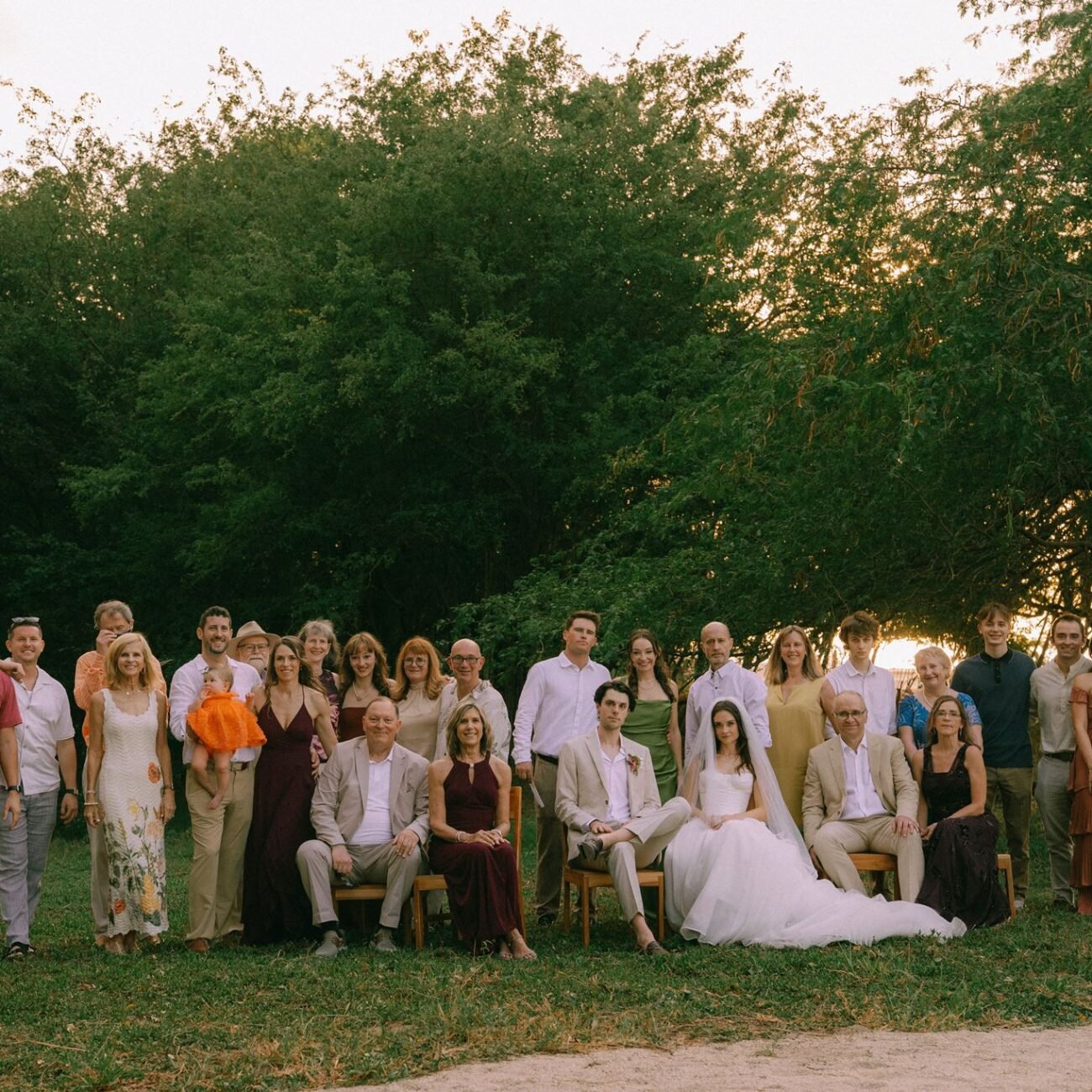 Family group portrait with the bride and groom seated in front, near the beach at Pangas Beach Club