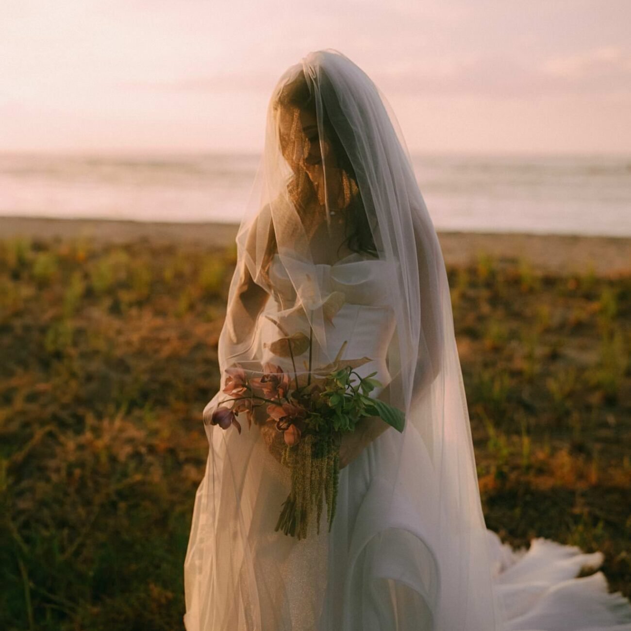 The bride at sunset holding her bouquet, backlit with her veil, Tamarindo