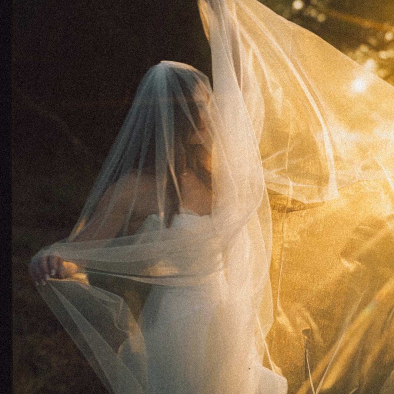 The bride’s veil lit by golden sunset light on the beach