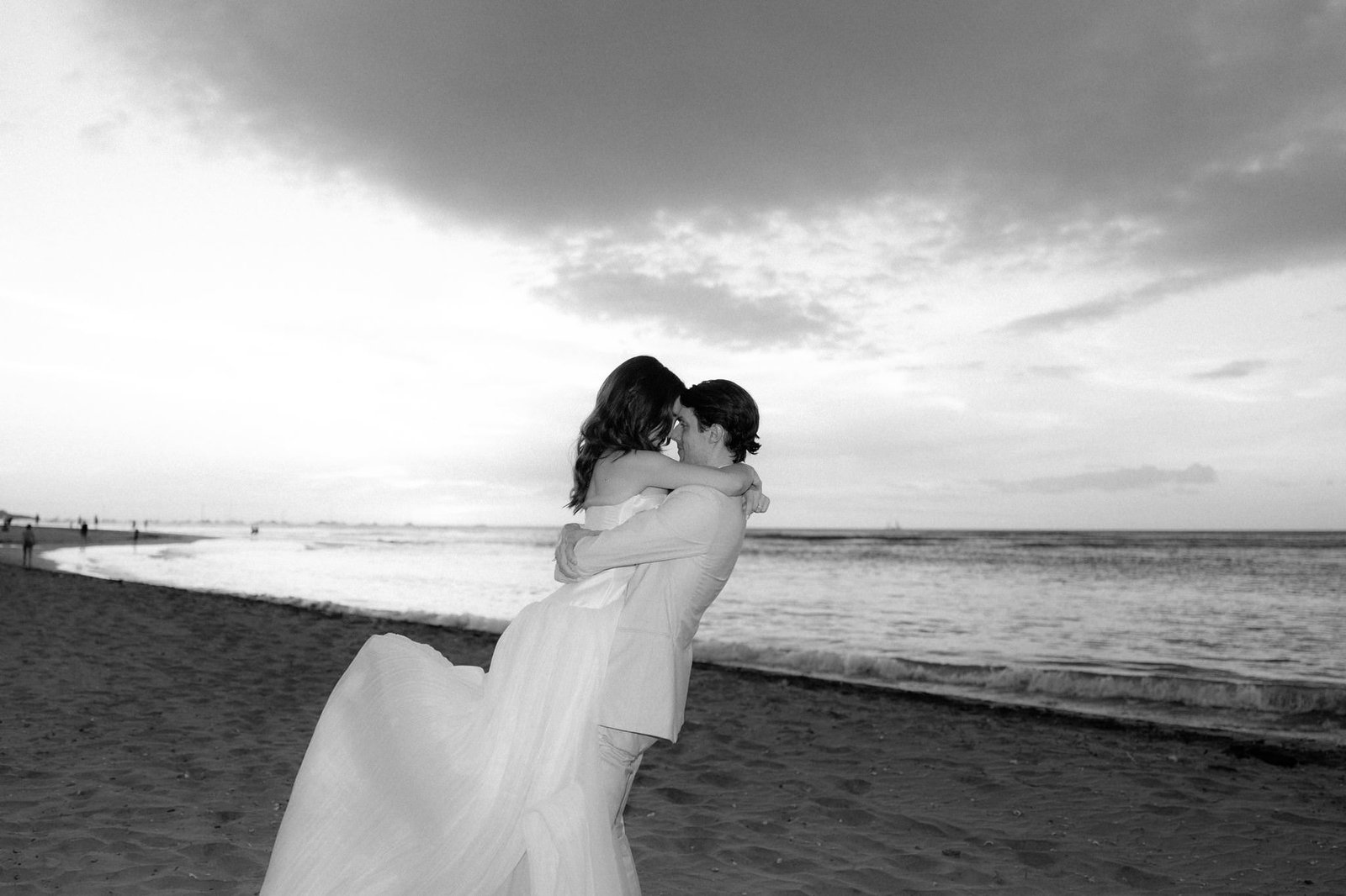 Black and white portrait of the groom lifting the bride on the beach at sunset in Tamarindo